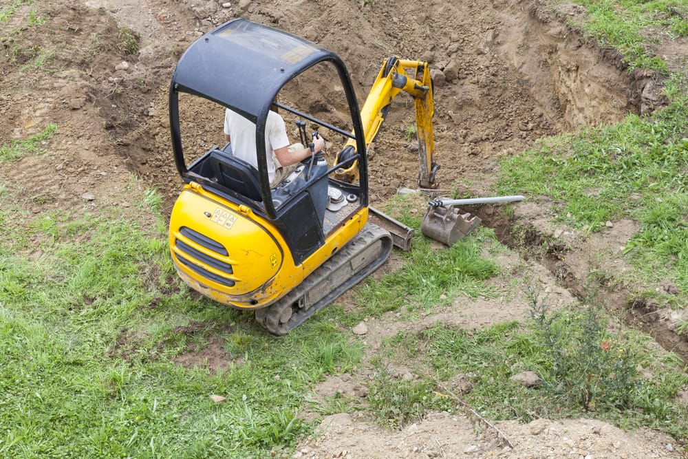 Mini digger excavating for building a steel shed